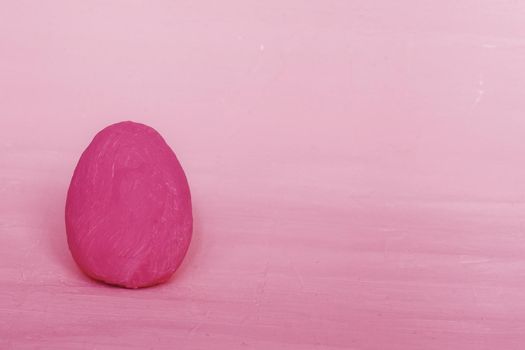 Decorative Easter dark pink egg on the background of fuchsia plaster. Greeting card Happy Easter.