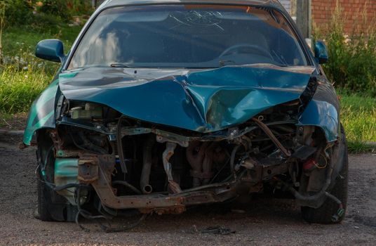 A blue car with a badly damaged bumper.