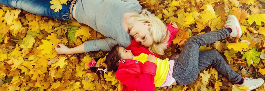 Mother and daughter in autumn yellow park.