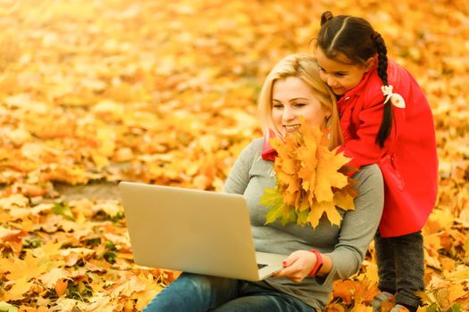 Urban woman and daughter with laptop in park. slim hipster woman in jeans using notebook. freelancer using communication technology remote work and eco-friendly lifestyle.