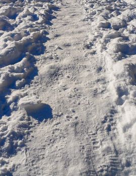 Snow texture with foot prints. Path in the snow in the field with many footprints from shoes.