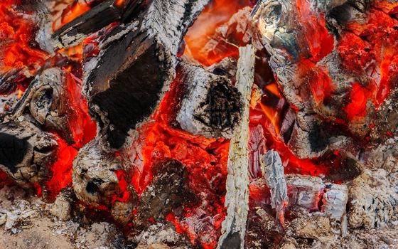 glowing coals close up at night. A smoldering fire with glowing embers of wood.