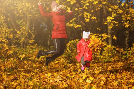 Young mother playing with her daughter in autumn park