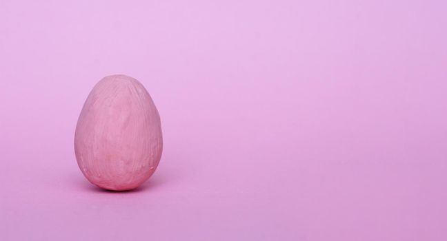 Dark pink decorative egg on a red background. Happy Easter background. Minimal Easter.