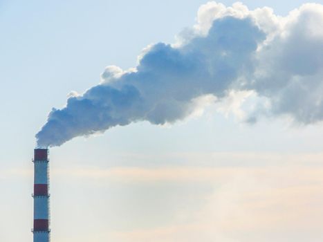 Smokestack against the sky. Chimney smoke on a blue sky.