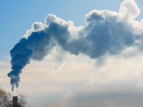 industrial chimneys with heavy smoke causing air pollution on gray sky background. Chimney white smoke on a blue sky.