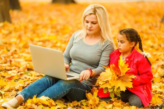 Urban woman and daughter with laptop in park. slim hipster woman in jeans using notebook. freelancer using communication technology remote work and eco-friendly lifestyle.