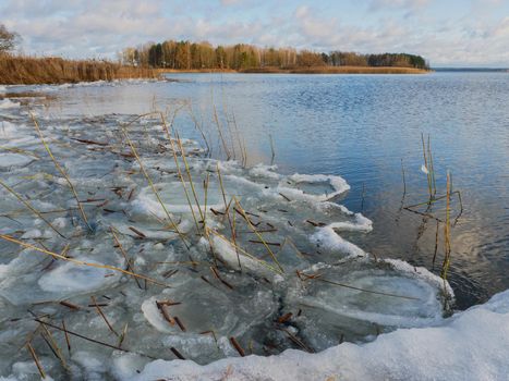 Spring lake with melting ice. Ice blocks on the shore.