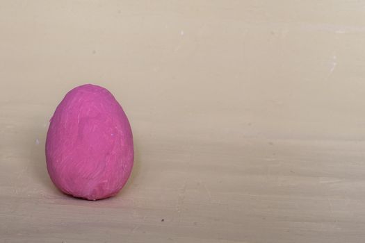 Dark pink decorative egg on a gray background. Painted Easter egg