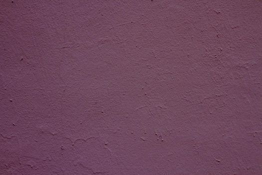 Old peeling paint on the wall. Mauve abstract background. Background from purple stucco.