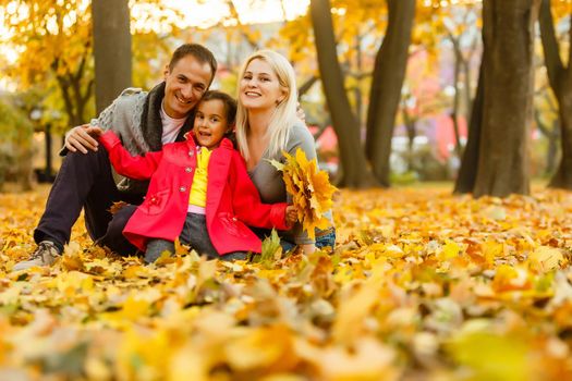 Happy family is sitting in beautiful autumn park