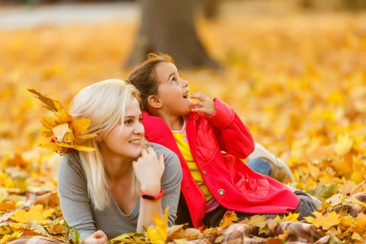 Young mother playing with her daughter in autumn park