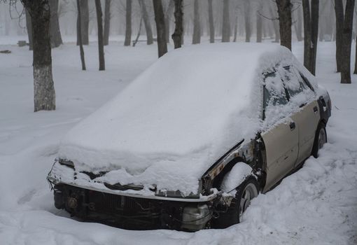 Old smashed car covered in snow. Abandoned car in the snow.