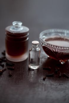 Clove face mask for prevention against acne and pimples on wooden surface in a glass bowl along with clove oil and some coconut oil.