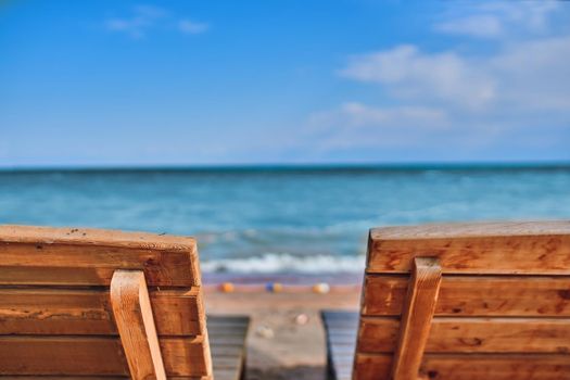 Sunbeds on the beach. Two wooden chairs for relaxing on the lake shore.