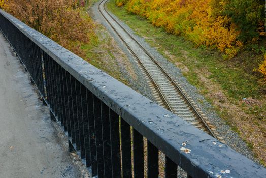 View from the bridge to the railway against the background of autumn trees. High quality photo