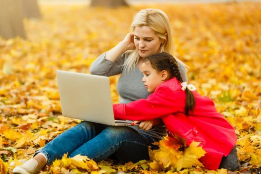 Urban woman and daughter with laptop in park. slim hipster woman in jeans using notebook. freelancer using communication technology remote work and eco-friendly lifestyle.