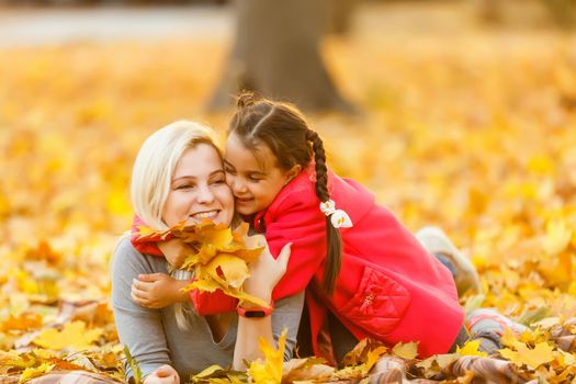 Young mother playing with her daughter in autumn park