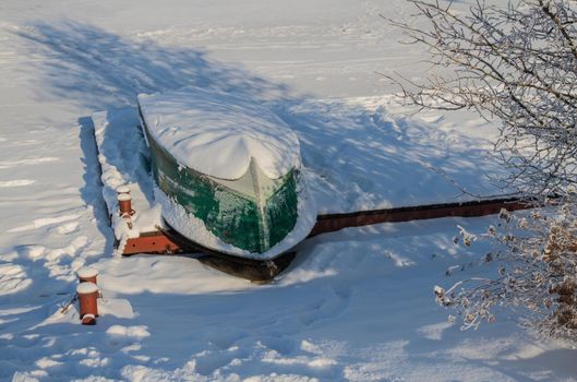 Snow-covered boat on the pier..Inverted boat under the snow...