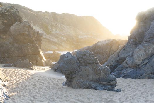 Haze in the rocks on the ocean in the rays of the setting sun. Landscape