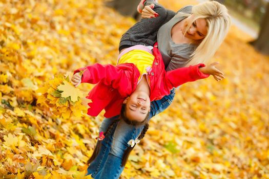 Happy family: mother and child little daughter play cuddling on autumn walk in nature outdoors