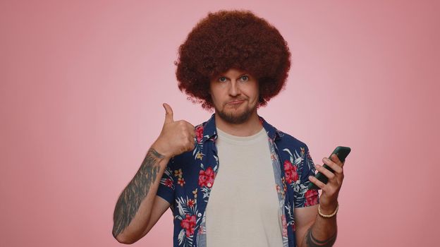 Handsome tourist young man using smartphone typing new post on web, browsing, searching, addiction of social networks, show thumbs up like, positive feedback, recommends wifi cellular connection 5G