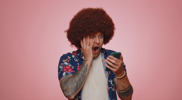 Happy excited joyful man in casual shirt use mobile cell phone typing browsing shouting say wow yes found out great big win, good news, lottery goal achievemen, celebrating success, winning