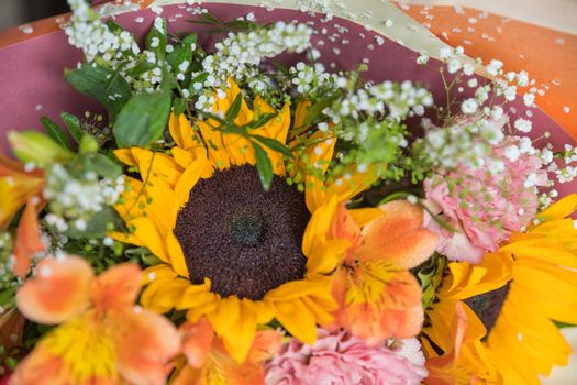 Hello August. Beautiful autumn bouquet with sunflowers and heart card close up on abstract light grey background.