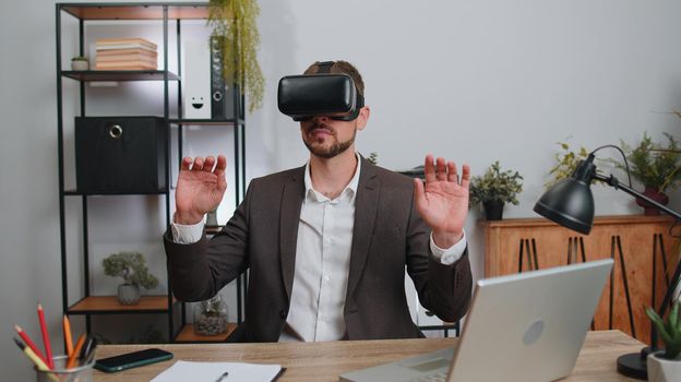 Businessman in suit working using virtual reality futuristic technology VR app headset helmet at home office. Freelancer man busy creating new architecture project. Remote education, study, learning