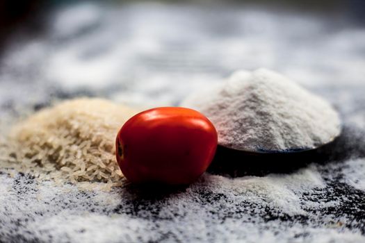 Face mask for oily skin on wooden surface consisting of rice flour,honey,tomato juice in a glass bowl along with some rice flour spread on the surface for greater effect.Horizontal shot.