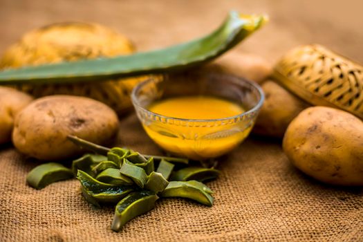 Homemade conditioner and shampoo for dandruff and scalp cleaning on jute bag's surface i.e. potato juice well mixed with aloe vera gel in a glass bowl along with raw potato and some aloe vera leaf.