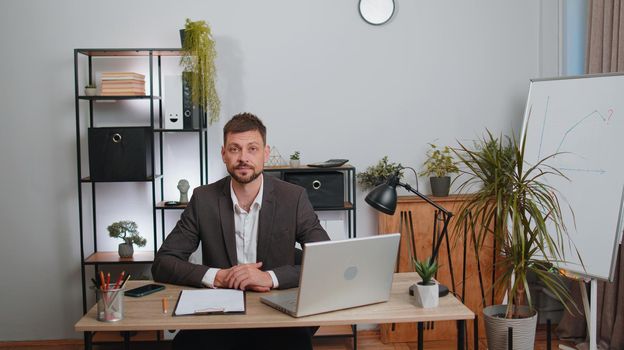 Businessman in suit thinking about an important creative project work decision at home office desk. Confident serious male manager freelancer man busy occupation looking through analytical reports