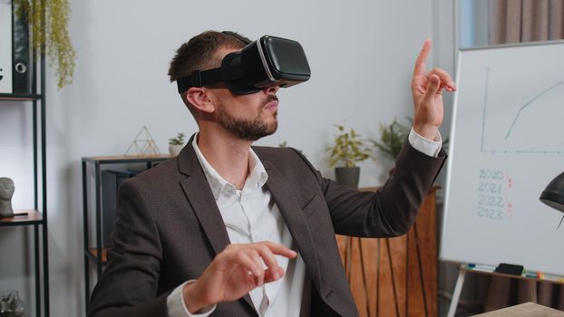 Businessman in suit working using virtual reality futuristic technology VR app headset helmet at home office. Freelancer man busy creating new architecture project. Remote education, study, learning
