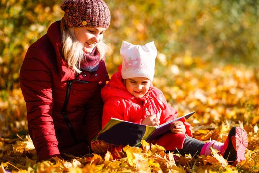 Mother daughter time. Soft focus shot of a mother and daughter reading a book together relaxing near the autumn park