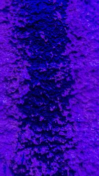 Purple flowed paint on a rough wall.