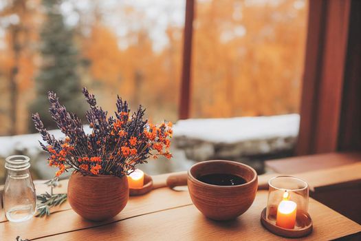 3D render of Autumn hygge home decor arrangement, concept of hygge and coziness, burning white fragrance candle on tray and lavender branches in a bottle vase on table at cozy home