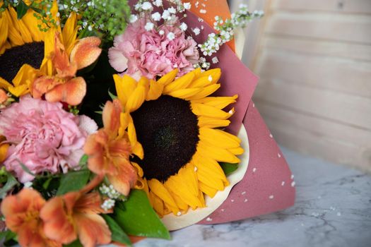 Hello August. Beautiful autumn bouquet with sunflowers and heart card close up on abstract light grey background.