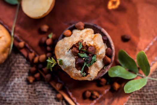 Famous Indian & Asian street food dish i.e. Panipuri snack in a clay bowl along with its flavored spicy water in another clay vessel. Entire consisting raw ingredients present on the surface.Top shot.