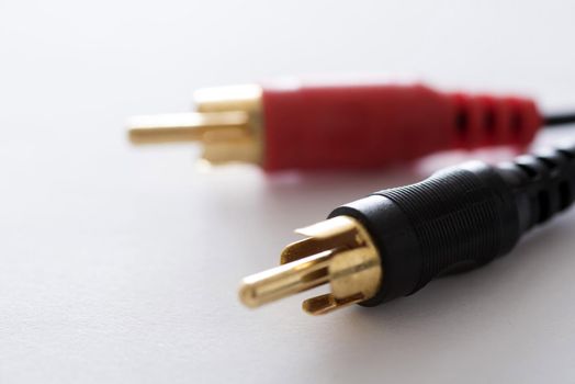 Black and red stereo phono plugs with gold metal connector close-up on white background