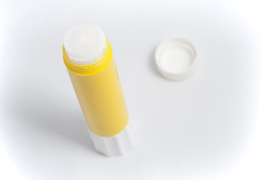 Opened yellow glue stick on white background