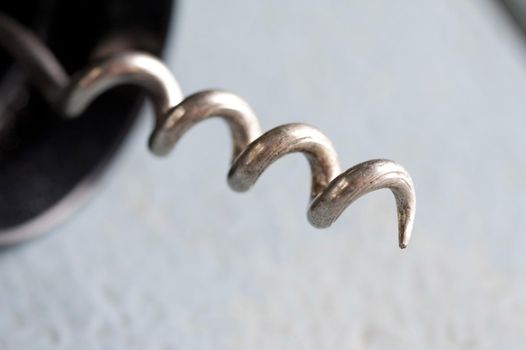 Close up on a steel corkscrew tip on a wine bottle opener over a textured white background with copy space