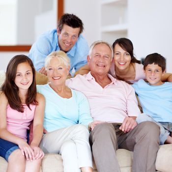 A proud, loving family enjoying time together. Three generations of family embracing one another on the lounge couch