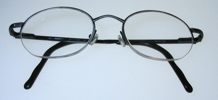 Close up on pair of simple folded thin metal frame eyeglasses over gray background