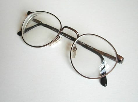 Pair or eyeglasses lying folded on a white background with copy space viewed high angle close up