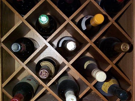 Wooden wine rack with individual partitions filled with bottles of a variety of different vintages and varieties of wine