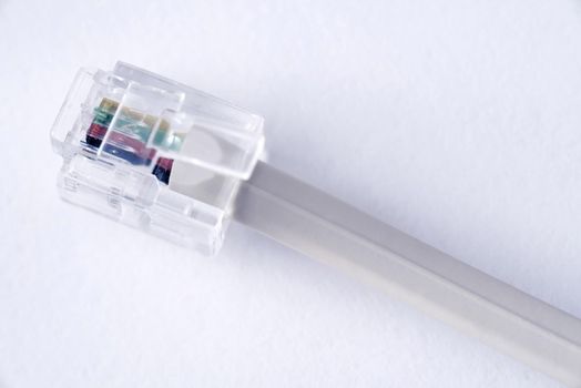 Transparent telephone plug on a cable showing the colored wires over white in a telecommunications concept