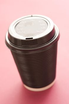 Plastic takeaway hot beverage container for coffee or cappuccino with a closed lid on a red background