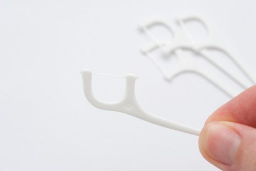 close up on a hand holding a dental flossing tooth pick