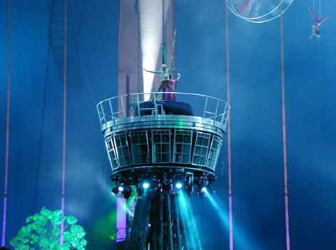 The centre stage of a nighttime circus show and performing acrobats.