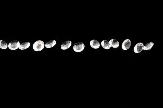Line of bright diamond like stones over black with copy space above and below them